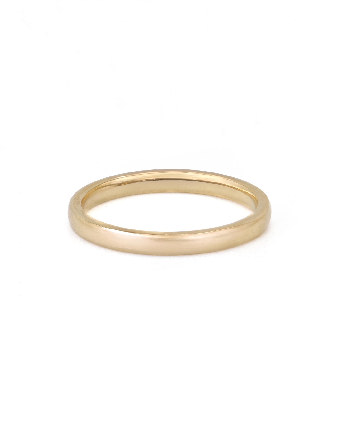 A simple gold band ring on a white background