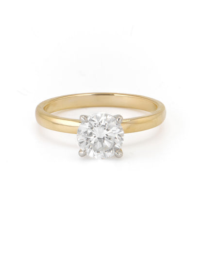 A round diamond solitaire engagement ring with a two-tone gold band, set in a 18K yellow gold setting.