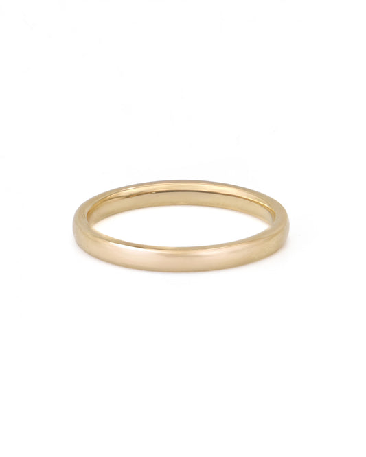 A simple gold band ring on a white background