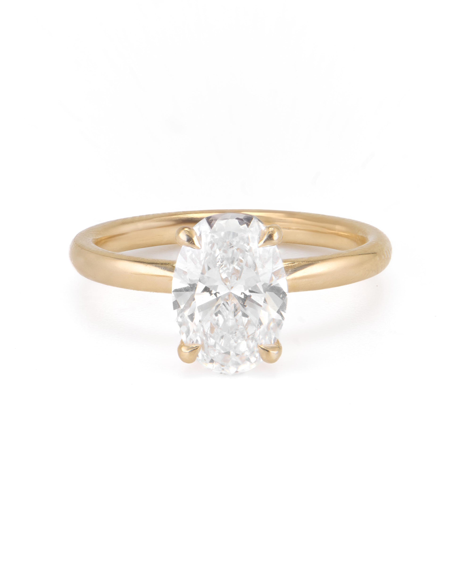 An oval solitaire engagement ring with a yellow gold band and a clear central diamond.