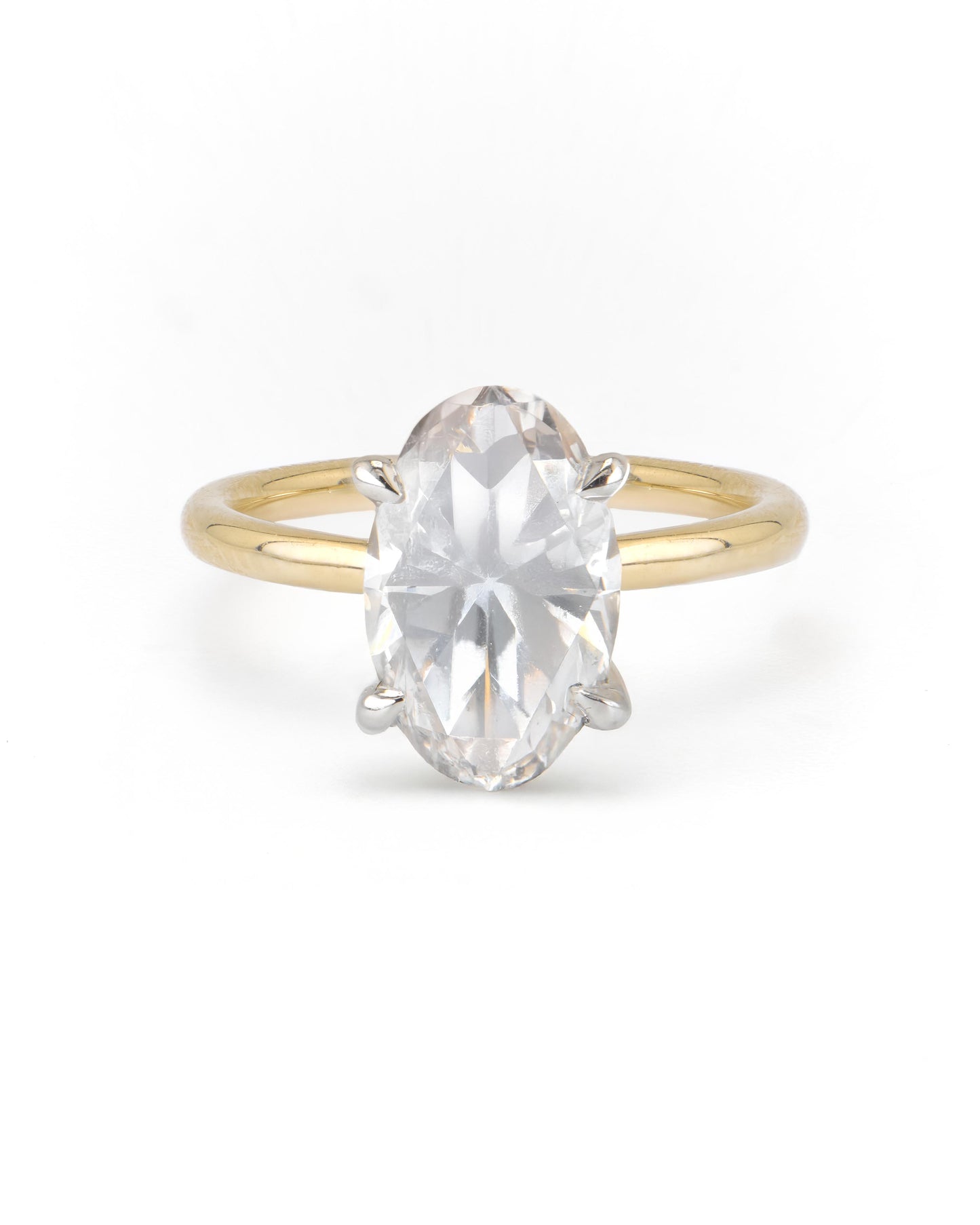 An oval two-tone solitaire engagement ring with a clear center diamond set in a gold band with a white gold head.