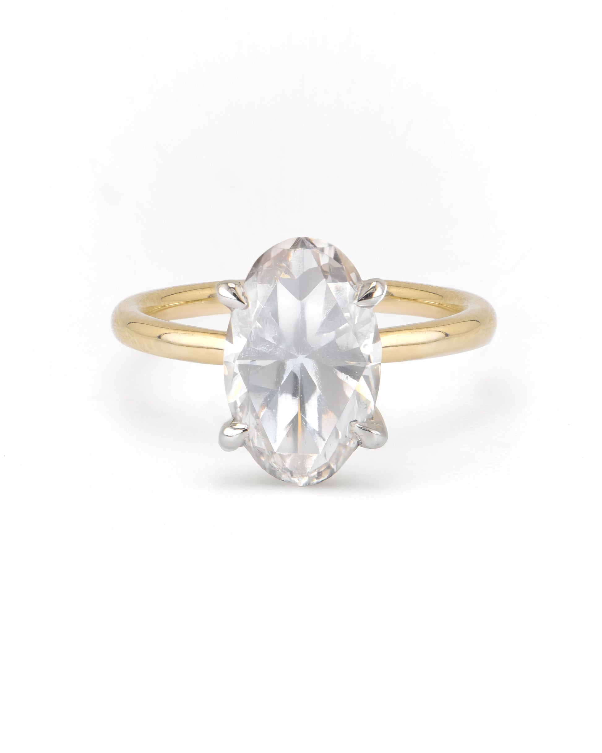 An oval two-tone solitaire engagement ring with a clear center diamond set in a gold band with a white gold head.
