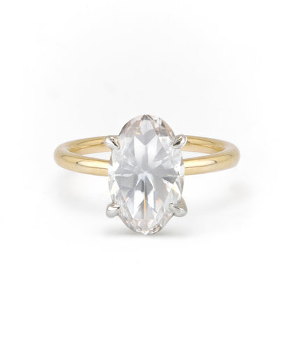 An oval two-tone solitaire engagement ring with a clear center diamond set in a gold band with a white gold head.
