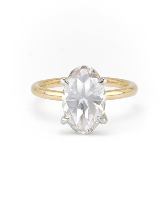 An oval two-tone solitaire engagement ring with a clear center diamond set in a gold band with a white gold head.