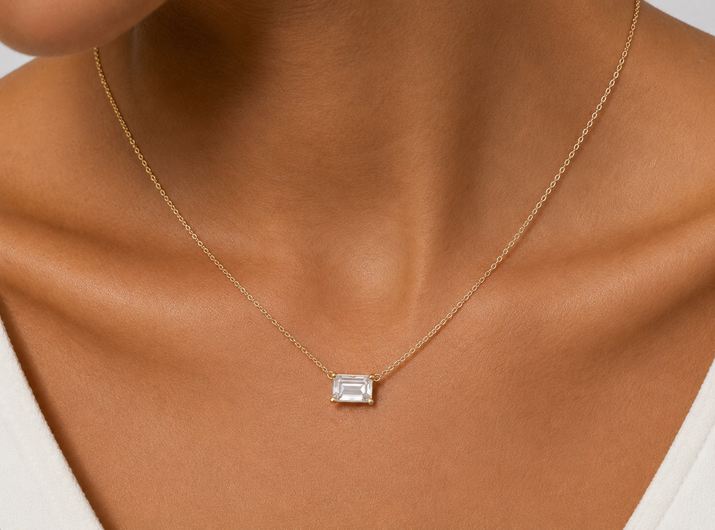 Emerald-cut diamond solitaire necklace worn on model, close-up