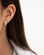 Emerald-cut diamond huggie earrings worn on model, close-up