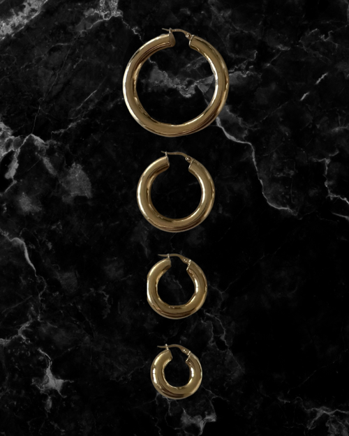 Set of gold hoop earrings on a dark marble surface