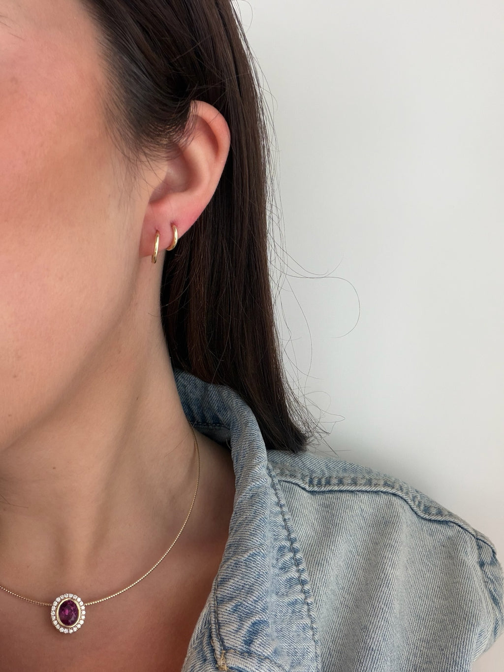 Gold huggie earrings worn on model, close-up