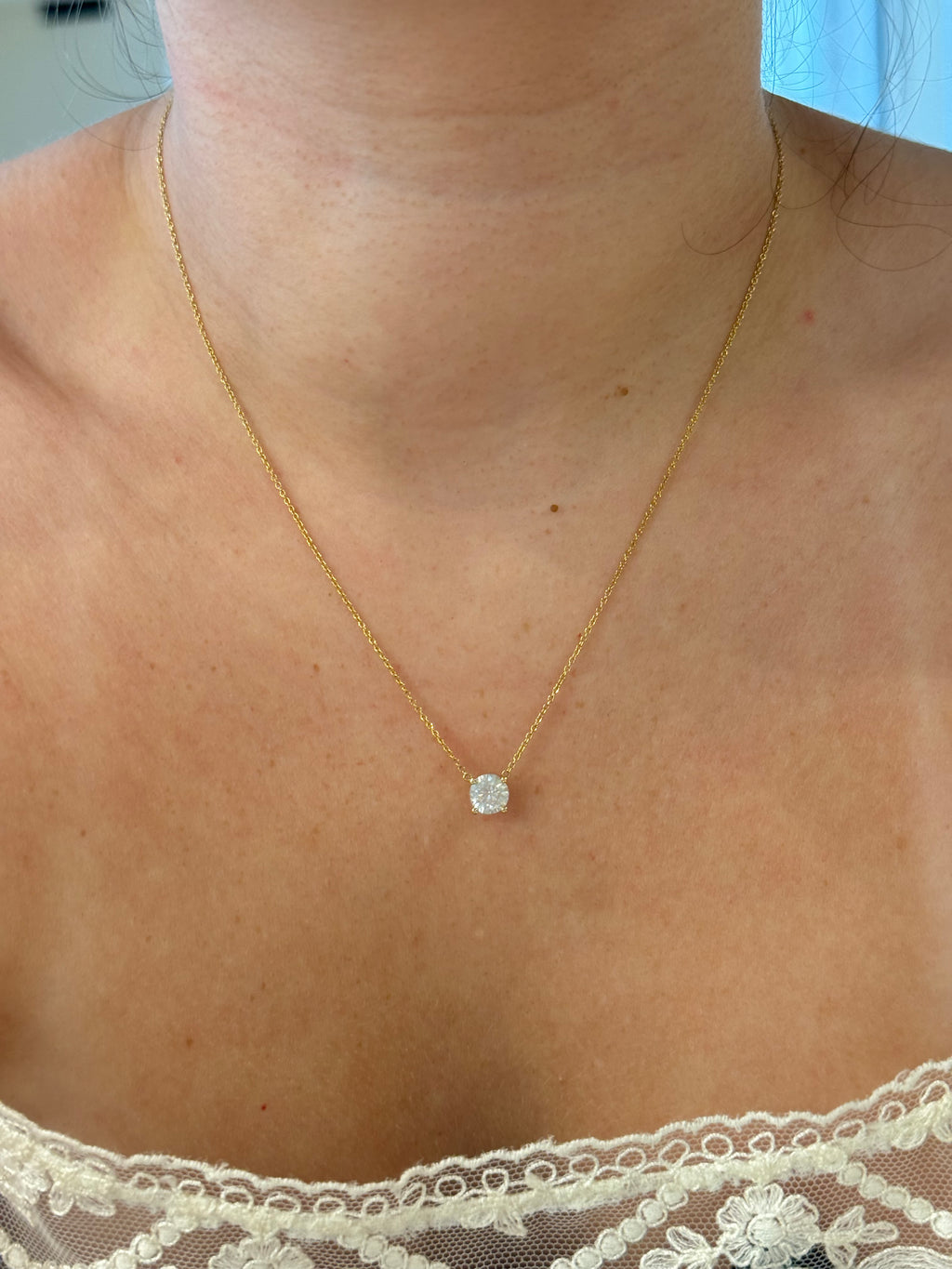 Floating diamond solitaire necklace worn on model, close-up