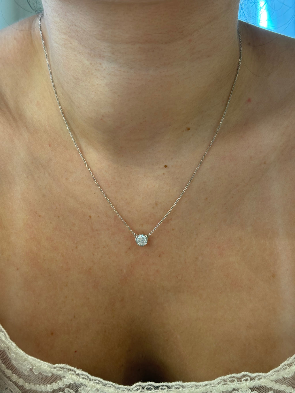 White gold bezel diamond necklace worn on model, close-up