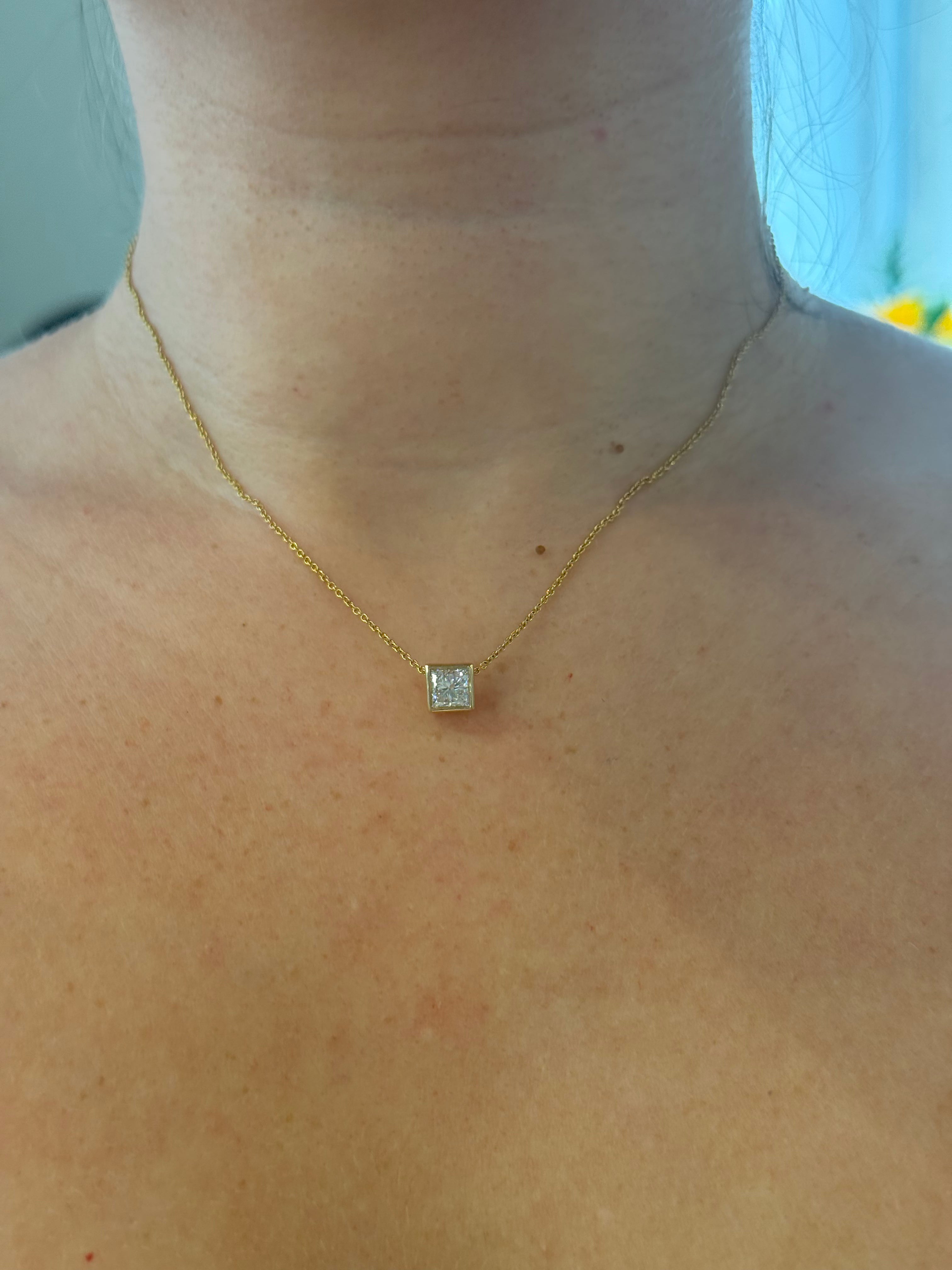Princess-cut diamond pendant worn on chain, close-up