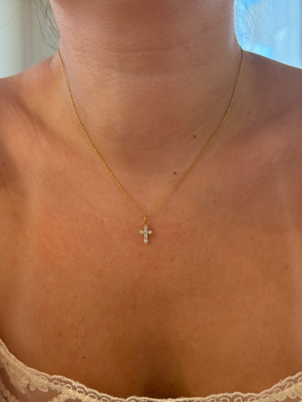 Diamond cross pendant worn on model, close-up