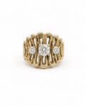 A yellow gold ring with a textured, wavy openwork design, featuring a central round diamond and two smaller round diamonds on either side, set against a plain white background.