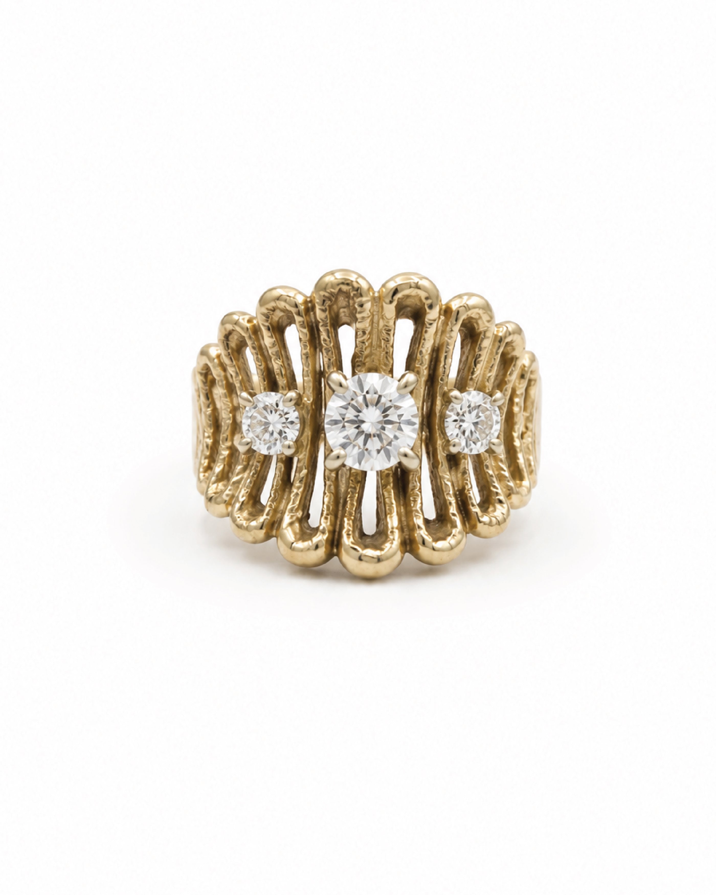 A yellow gold ring with a textured, wavy openwork design, featuring a central round diamond and two smaller round diamonds on either side, set against a plain white background.