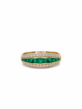Gold ring with green gemstones and white stones on a white background