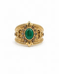 A gold ring with a central oval green emerald stone, surrounded by small diamonds and ornate gold detailing, shown on a plain white background.